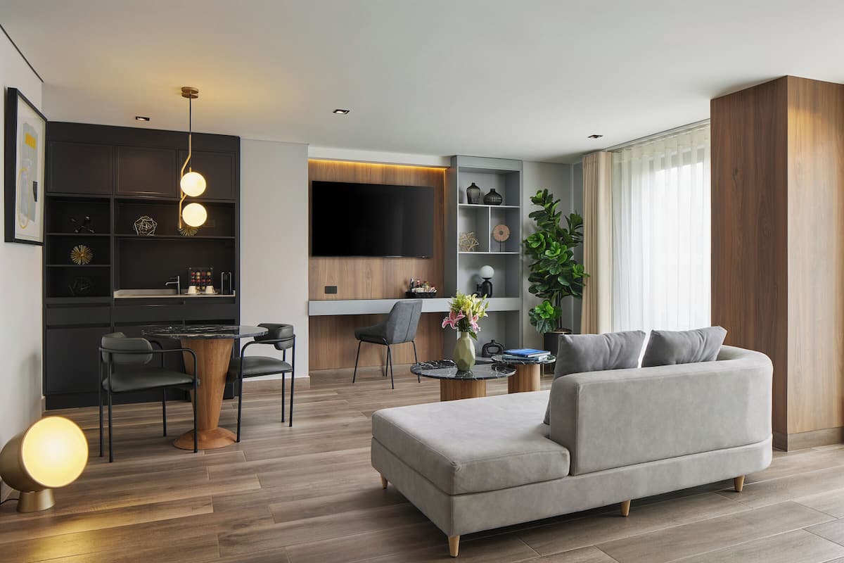 A modern living room with a grey sofa, wooden coffee table, and a dining area with a black table and chairs.