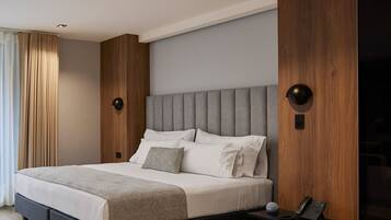 Un dormitorio moderno con una cama grande, paneles de madera y una mesita de noche con un teléfono.