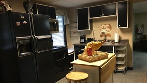 A kitchen with black appliances, a wooden stool, and a welcome sign. - Private apartment in Great Neighborhood (Rome)
