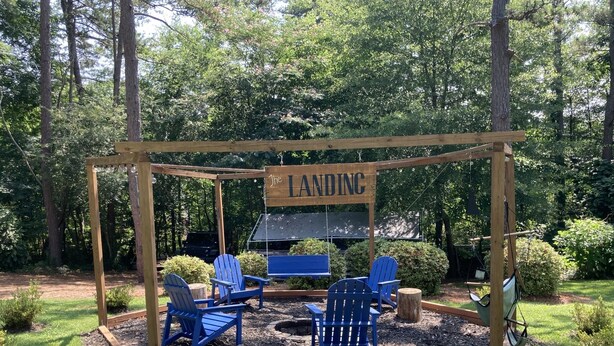 A wooden gazebo with a sign reading "The Landing," surrounded by blue Adirondack chairs and a fire pit. - Private apartment in Great Neighborhood (Rome)