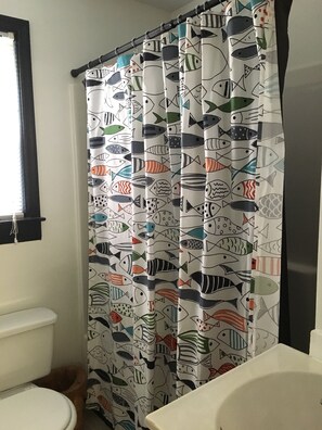 A bathroom with a shower curtain featuring a fish pattern.
