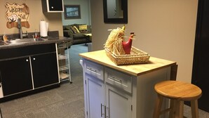 A kitchen with a wooden counter, a sink, and a bar stool. There is a woven basket with a rooster decoration on the counter. - Private apartment in Great Neighborhood (Rome)