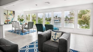 A spacious living room with a dining area, large windows, and a view of the water. - Belle Vista (Madeira Beach)