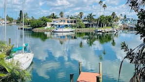 A marina with docked boats, a wooden pier, and a backdrop of houses and palm trees under a clear sky. - Belle Vista (Madeira Beach)