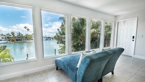 A spacious living room with a large window overlooking a marina and water. - Belle Vista (Madeira Beach)