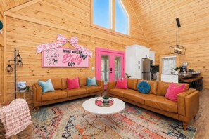 A cozy cabin interior with a wooden interior, a pink door, a kitchen area, and a living room with two sofas and a coffee table. - Dolly Glam 8 Min 2 Dllywd Hot Tub Karaoke IGWorthy (Sevierville)
