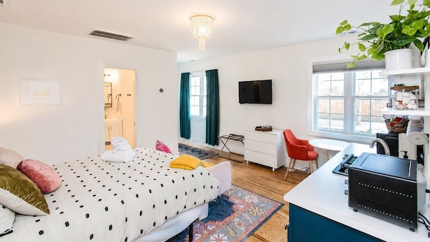 Une chambre à coucher moderne avec un lit, un bureau, une télévision et une fenêtre.