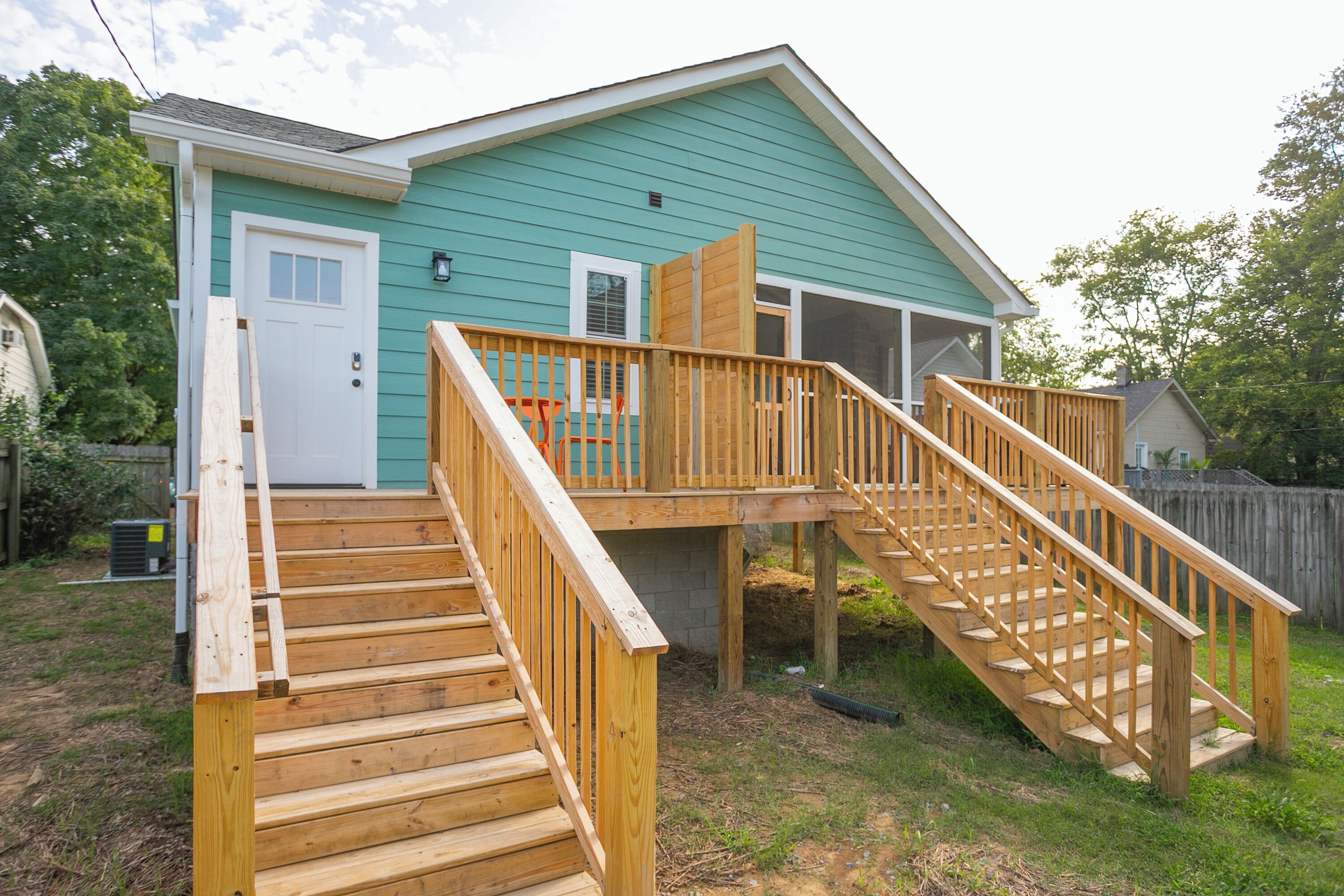 Une maison à deux étages avec une terrasse en bois et un escalier.