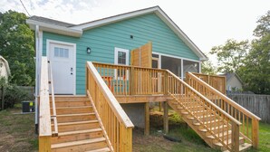 Une maison à deux étages avec une terrasse en bois et un escalier.
