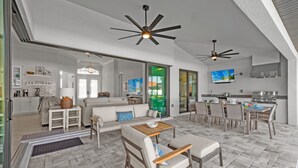 A spacious living area with a sofa, chairs, a dining table, and ceiling fans.