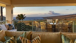 A balcony with a view of the sea, wicker furniture, and a sofa with patterned cushions. - Mauna Kea Waiulaula I201- Stunning Ocean & Golf Views - New Furnishings (Kamuela)