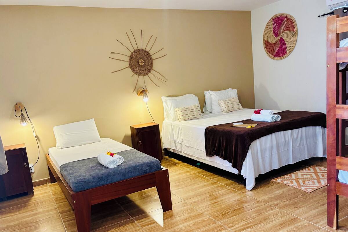 Una habitación de hotel con dos camas, una lámpara fijada en la pared y suelo de madera.