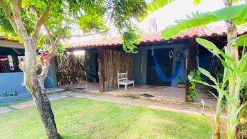 Relax in a serene garden setting with a lawn and lush plants, surrounded by a traditional architectural style and a rustic fence.