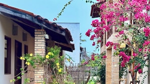 A narrow pathway flanked by buildings with brick walls and wooden railings, leading to a thatched-roof structure. - Pousada Morada das Dunas (Barreirinhas)