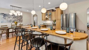 A modern kitchen with a central island, bar stools, wooden cabinets, and stainless steel appliances. - Craftsman | Int Designed | AC | Hottub | Epic yard (Flagstaff)