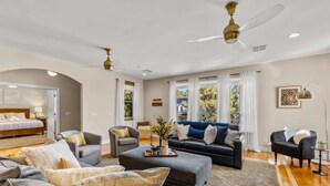 A spacious living room with a large grey sofa, a blue sofa, and a grey armchair. There is a wooden coffee table with decorative items, and a ceiling fan is visible. - Craftsman | Int Designed | AC | Hottub | Epic yard (Flagstaff)