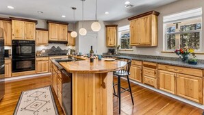A spacious kitchen with wooden cabinets, a central island, and pendant lighting. - Craftsman | Int Designed | AC | Hottub | Epic yard (Flagstaff)