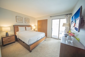 A hotel room with a bed, bedside tables, a desk, a chair, a TV, and a window with curtains. - Flying Dutchman 1115 (Keystone)