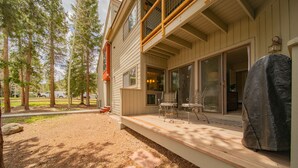 A covered deck with outdoor furniture, a barbecue grill, and a view of a house with sliding glass doors. - Flying Dutchman 1115 (Keystone)