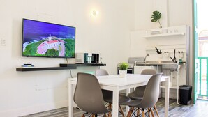 Eine moderne Küche mit Mikrowelle, Herd und Spüle. Ein Esstisch mit Stühlen und ein an der Wand befestigter Fernseher, der eine Landschaft zeigt.