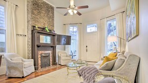 A living room with a fireplace, two armchairs, a sofa, a glass coffee table, and a ceiling fan. - Perfect Location: Inviting Uptown New Orleans Apt! (New Orleans)