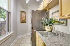 Una cocina con refrigerador de acero inoxidable, encimera de granito y una planta en maceta.