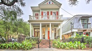 A two-story house with a front porch, columns, and a red door. - Perfect Location: Inviting Uptown New Orleans Apt! (New Orleans)