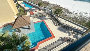Een resort met meerdere zwembaden, ligbedden en uitzicht op het strand.