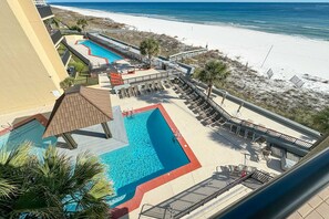 Un complexe hôtelier doté de plusieurs piscines, de chaises longues et offrant une vue sur la plage.