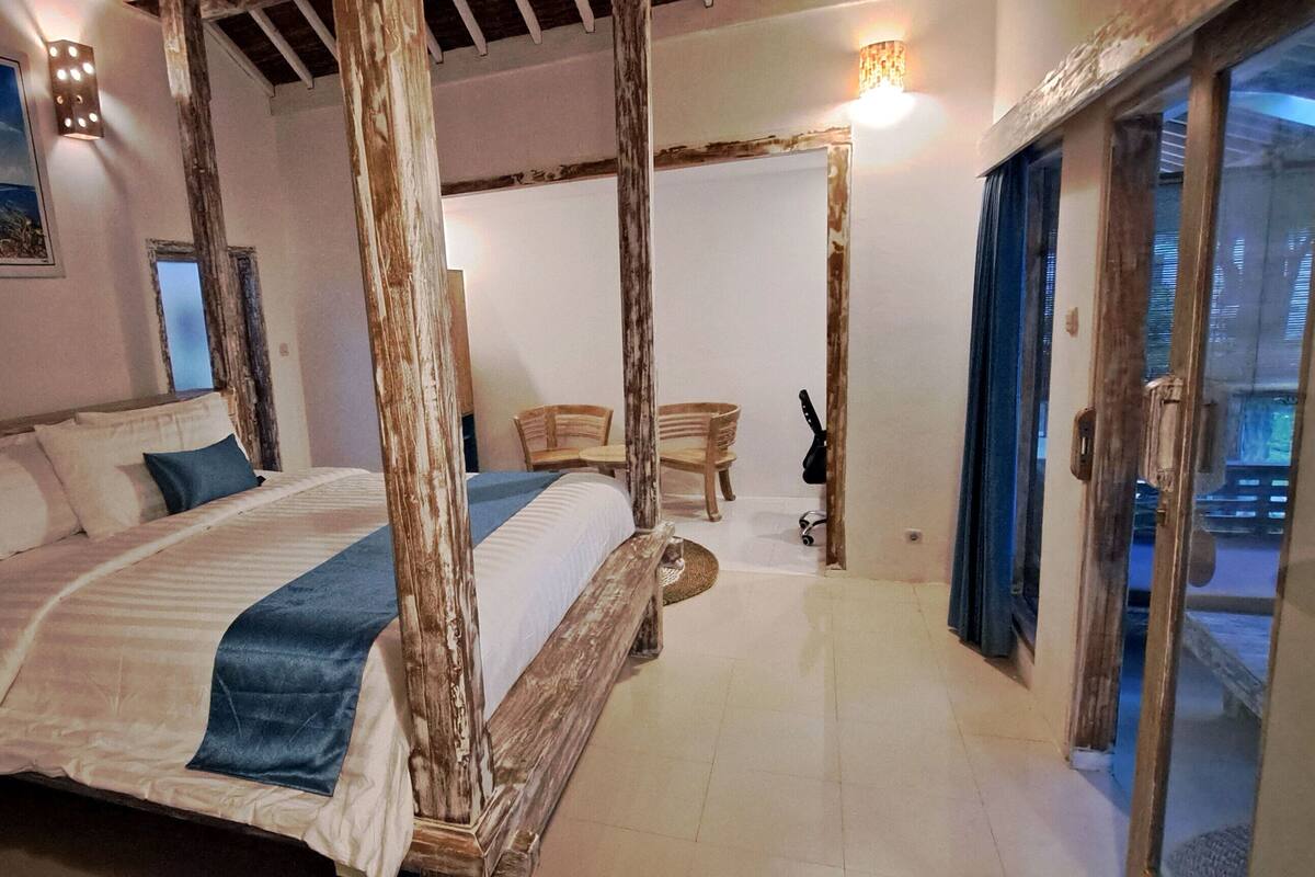 Une chambre avec un grand lit, des meubles en bois et une vue sur l’extérieur.