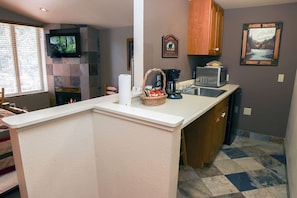 Modern kitchen with microwave, coffee maker, and TV, set against a neutral backdrop.