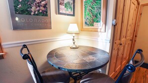 Een kleine ronde tafel met twee stoelen, een lamp en lijstwerken aan de muur.