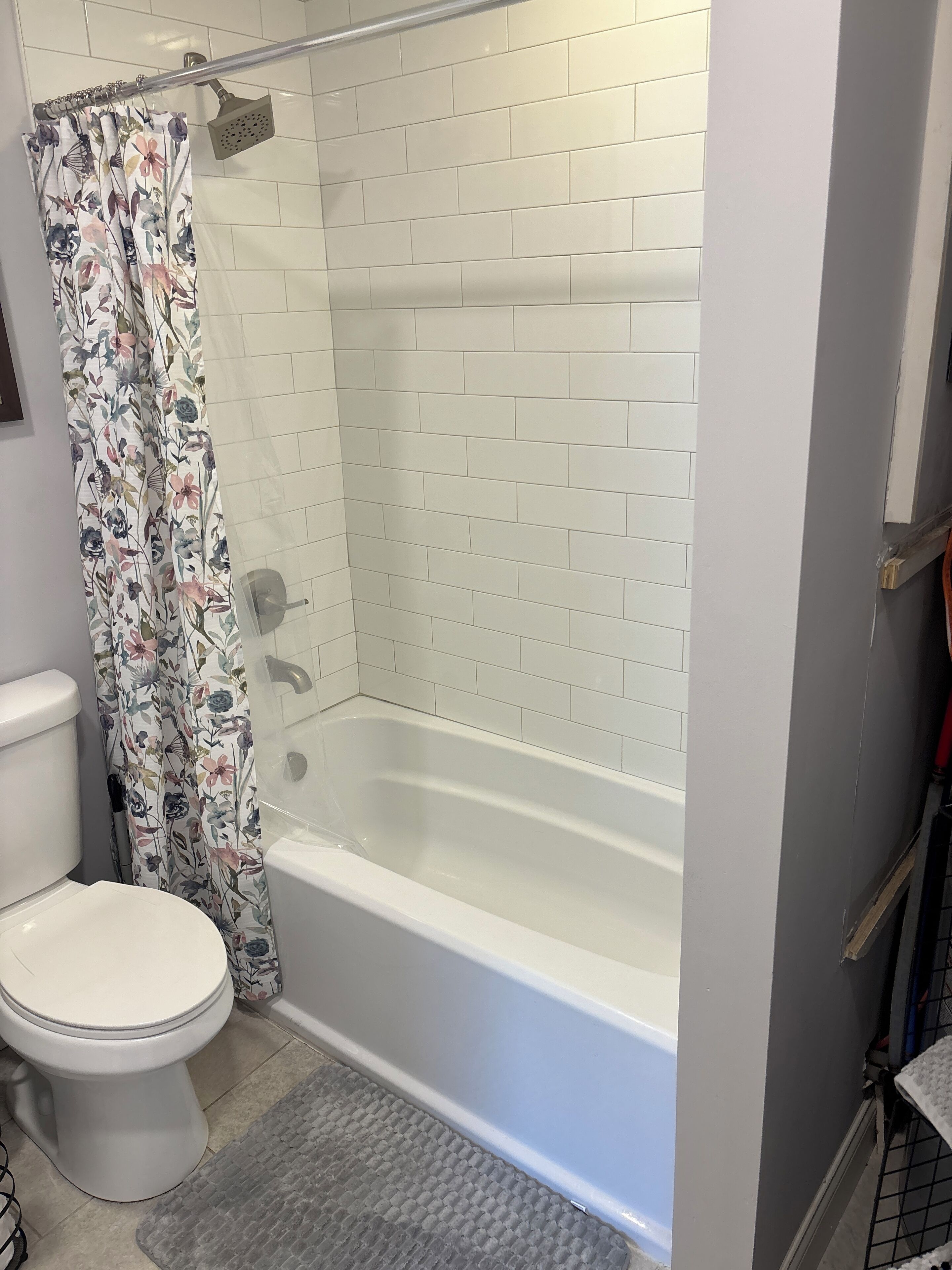 Un baño con inodoro blanco, bañera y cortina de ducha con estampado floral.