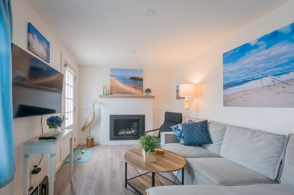 A modern living room with a fireplace, a sofa, a coffee table, and artwork on the walls.