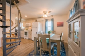 A compact kitchen with a dining area, a ceiling fan, and a spiral staircase.