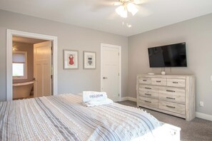 A bedroom with a bed, a dresser, a television, and two framed pictures on the wall. - Walk to Water with Hot Tub! (Yarmouth)