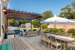 A covered outdoor patio with a pergola, seating area, and a table with chairs. - Walk to Water with Hot Tub! (Yarmouth)