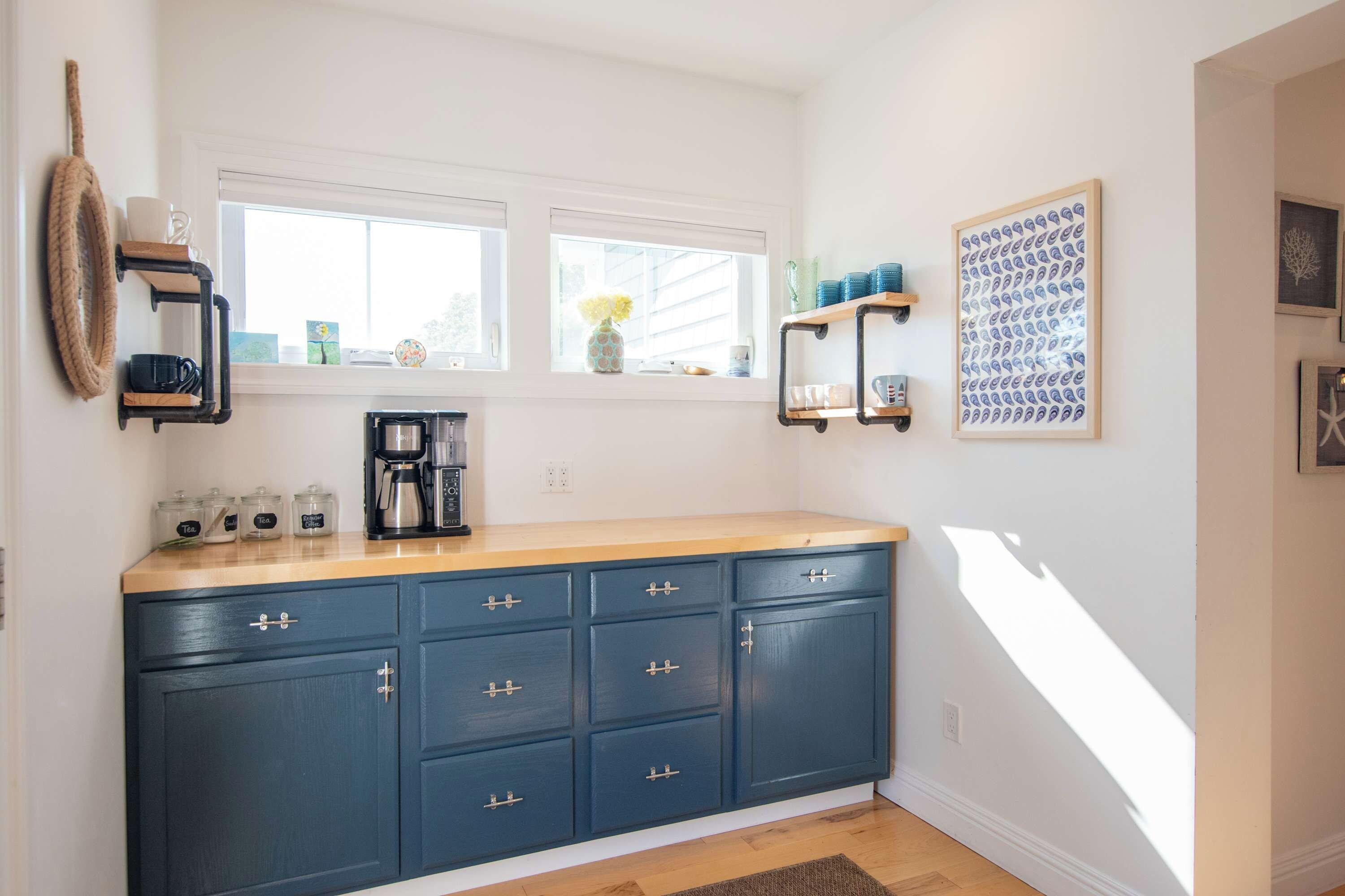 Una cocina con un mueble azul, una cafetera y una ventana con vistas.