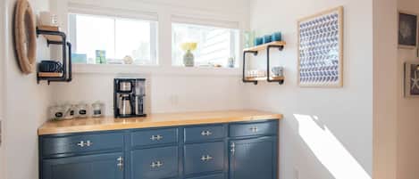 Una cocina con un mueble azul, una cafetera y una ventana con vistas.