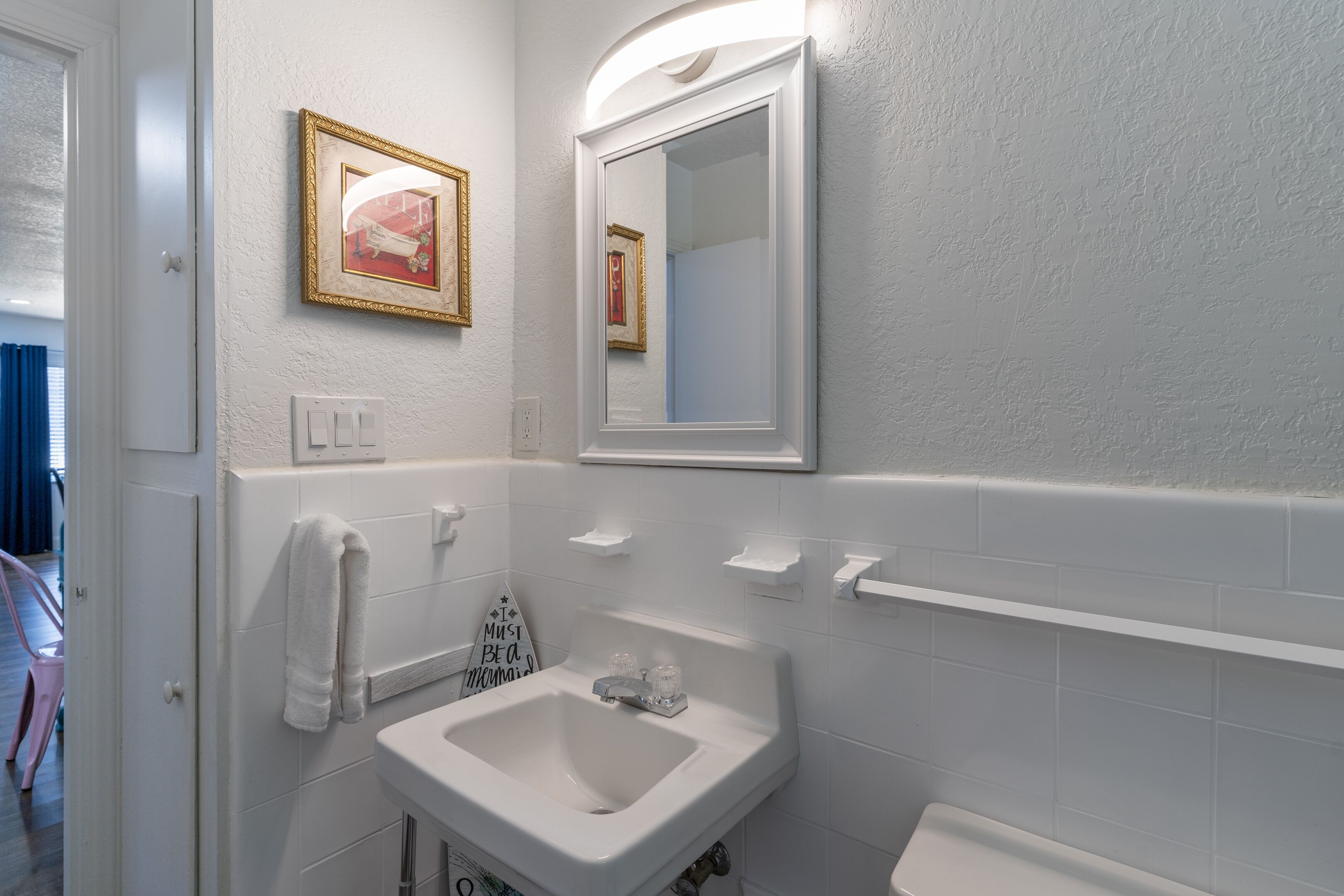 Une salle de bain avec un lavabo blanc, un miroir et un porte-serviettes.