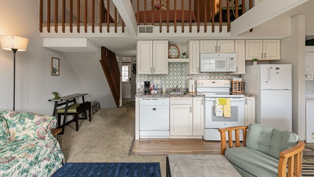 Cocina compacta con armarios blancos, microondas y refrigerador.