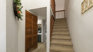 Una escalera con alfombra, barandillas de madera y un aplique en la pared.