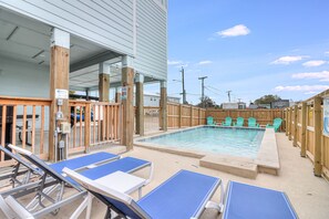 Ein Pool im Freien mit Holzliegen und Lounge-Stühlen.