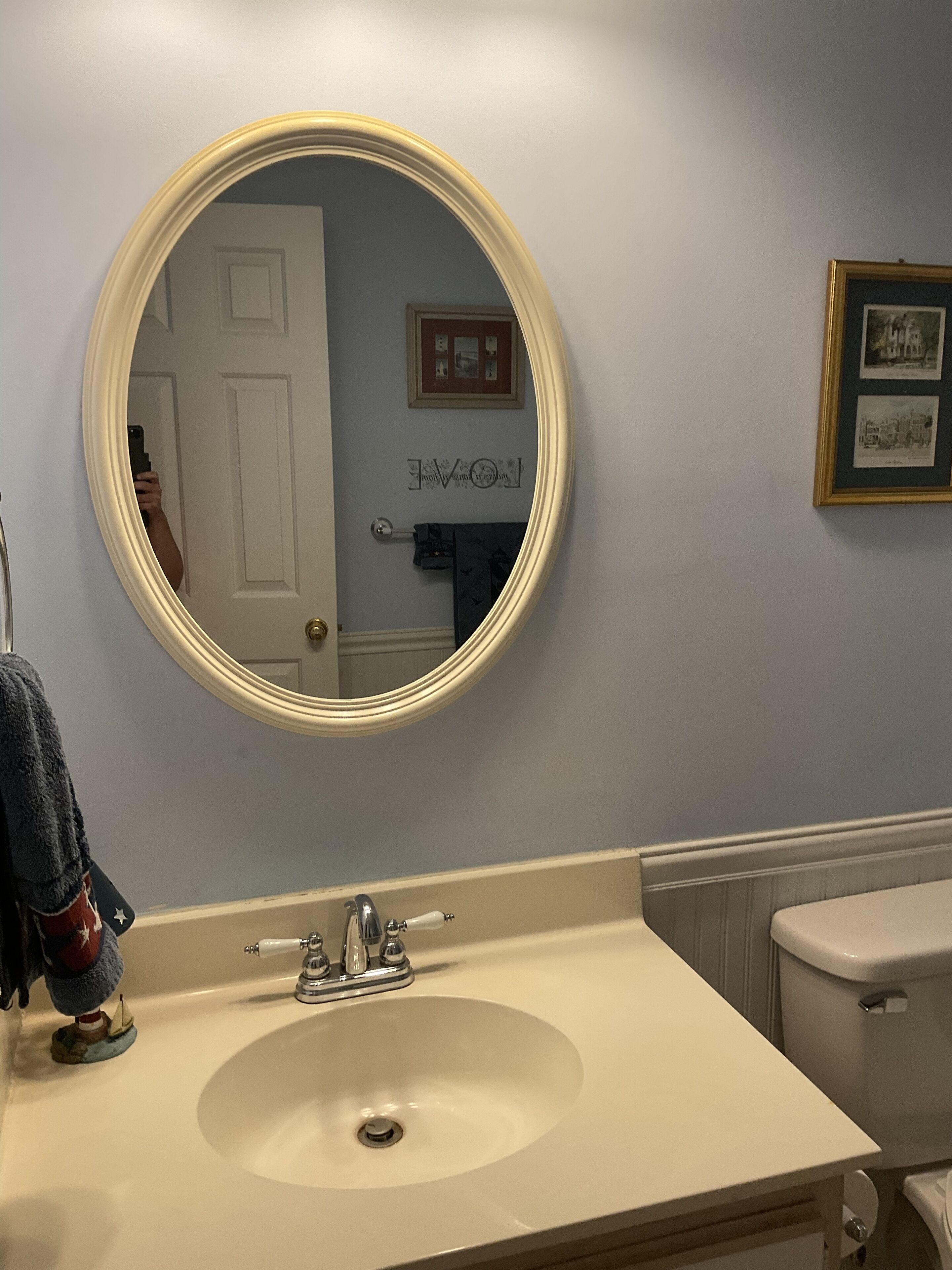 Ein Badezimmer mit rundem Spiegel, Waschbecken und Toilette.