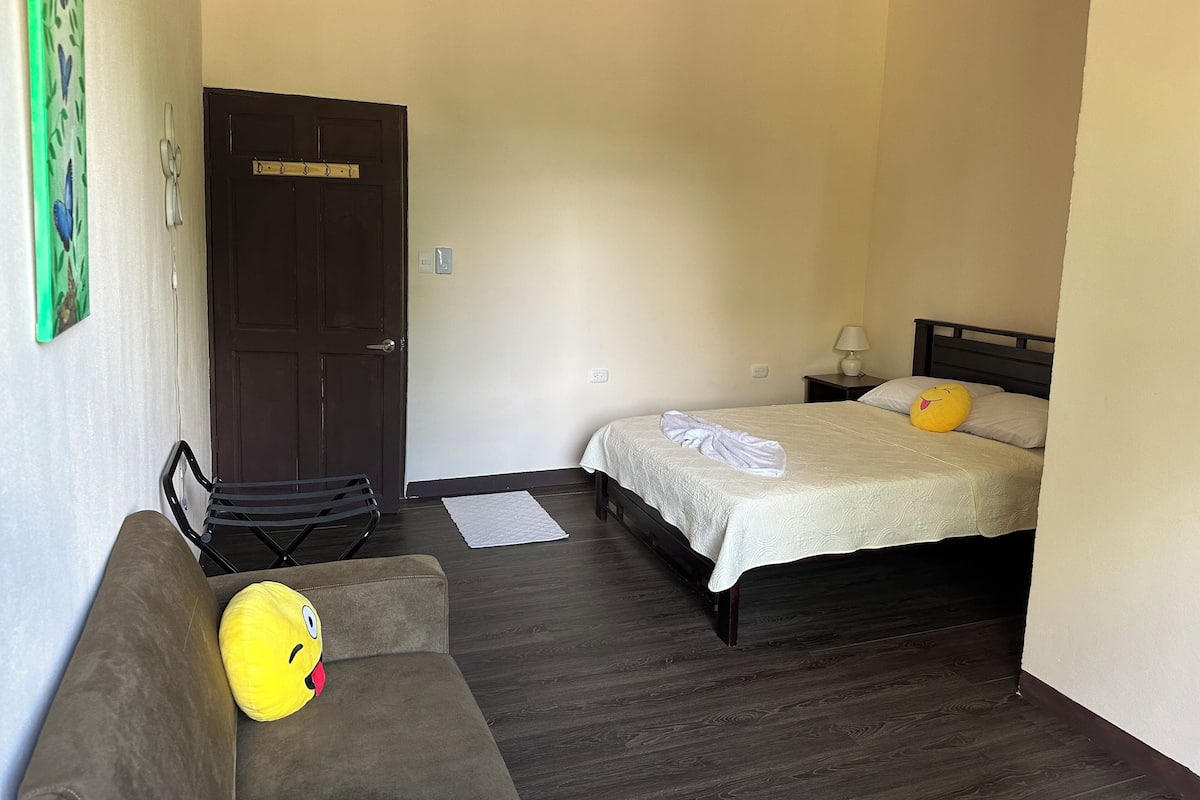Ein Schlafzimmer mit Bett, Stuhl, Tür und einer Wandlampe.