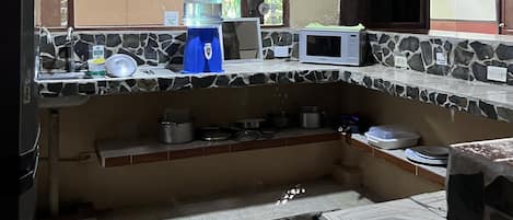 A kitchen with a stone countertop, a water dispenser, a microwave, and a sink.