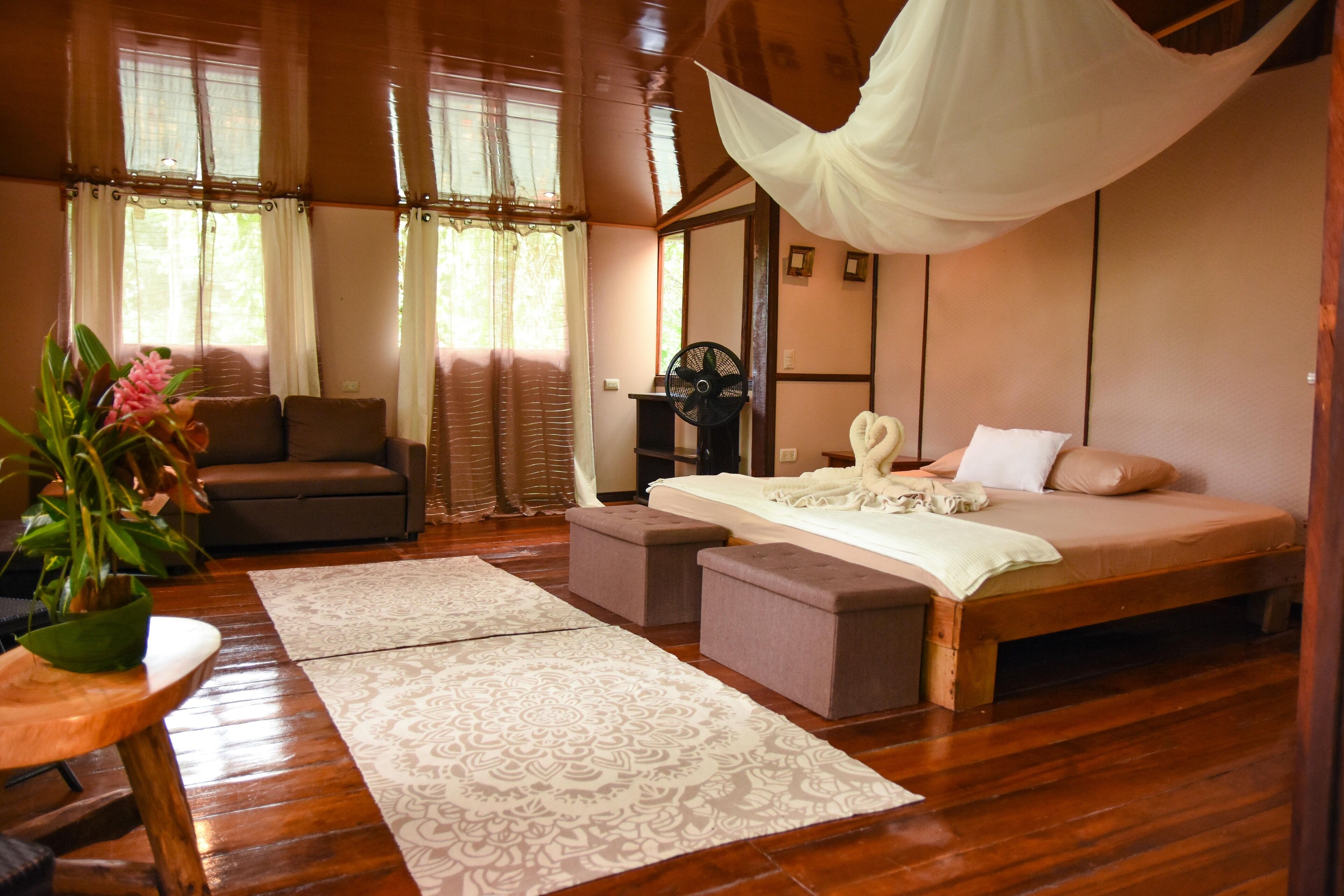 A bedroom with a bed, bedside table, and a large window with curtains.