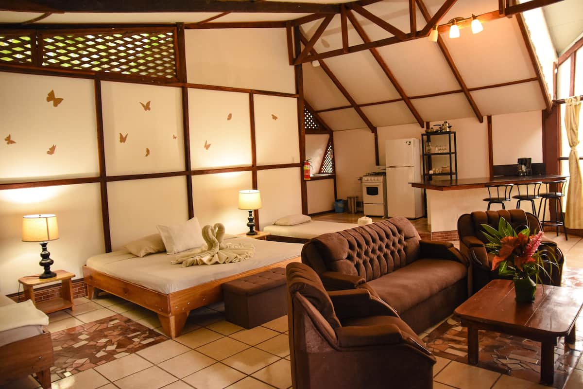 Ein gemütliches Hotelzimmer mit Bett, einer Couch, einem kleinen Tisch und einer Küchenzeile im Hintergrund.