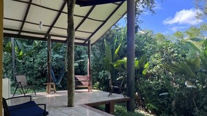 Une terrasse extérieure dotée d’un espace salon couvert, d’un hamac et d’un fauteuil suspendu.