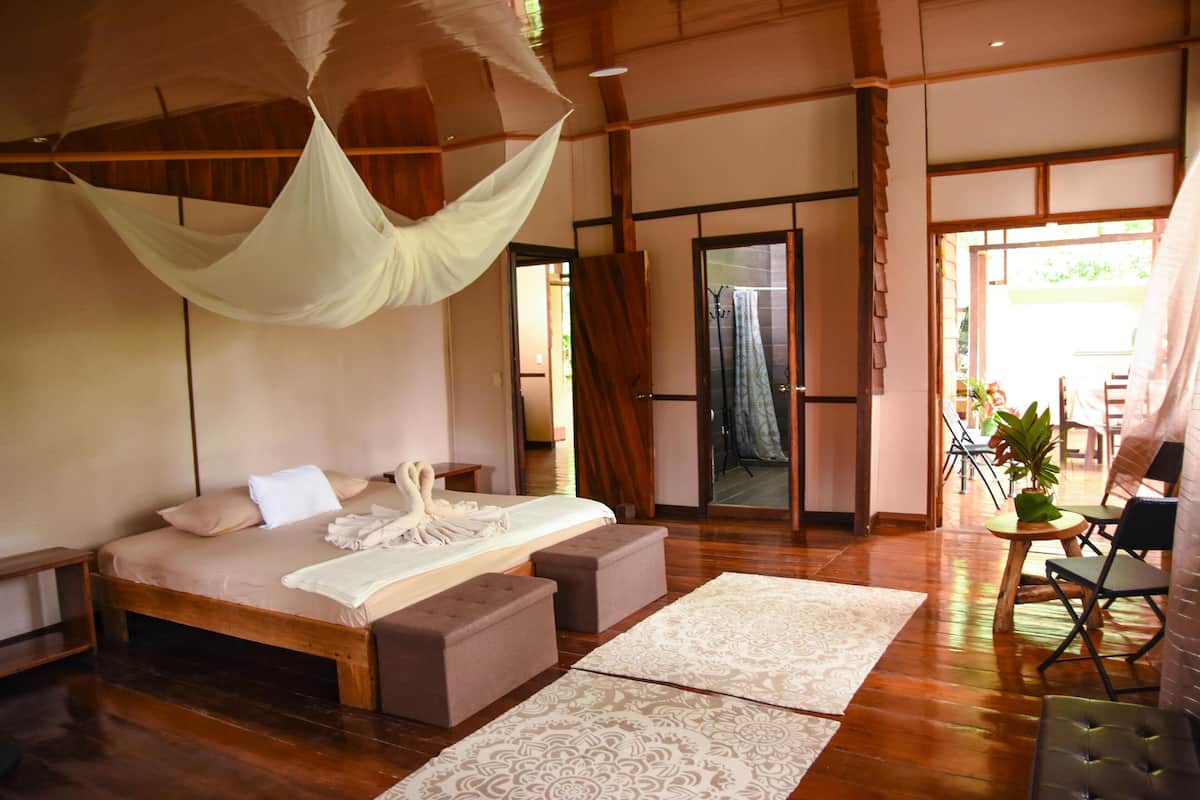 Ein Schlafzimmer mit einem großen Bett, Holzboden und einem Baldachin.